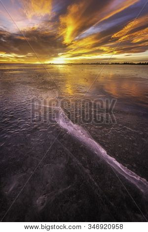 Colorful Sunrise On The Frozen Lake With Ice Cracks Glowing