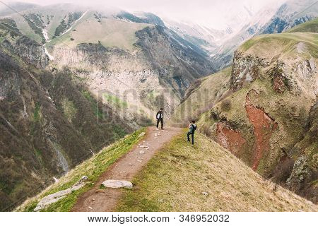 Mtiuleti Region, Georgia - May 21, 2016: Two Tourists Are Photographed On Edge Of The Gudskoye Gorge