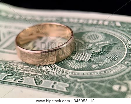 The Wedding Ring Lies On A Dollar Bill. Gold Ring On American Dollars. Concept: Marriage Of Convenie