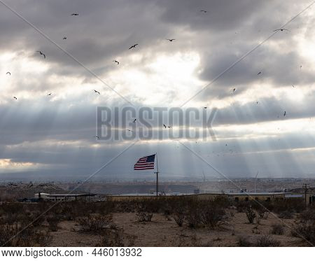 Dramatic Sunbeams With A Sky Filled With Crows Over An American Flag