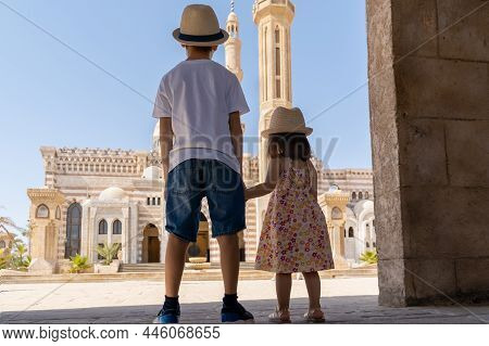 A Boy And A Girl Standing In Front Of El Mustafa Mosque And Looking At It