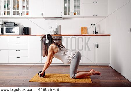 Pregnant Doing Workout On Orange Fitness Mat. Pragnant Yoga At Home In The Kitchen. Pregnant In Whit