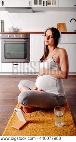 Pregnant Doing Workout On Orange Fitness Mat. Pragnant Yoga At Home In The Kitchen. Pregnant In Whit