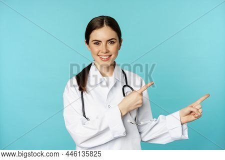 Portrait Of Young Professional Doctor, Woman Hospital Worker, Pointing Fingers Right, Showing Logo, 