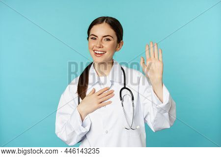 Friendly Smiling Woman Doctor Raising Hand, Name Herself, Introducing, Standing In Lab White Coat Ag