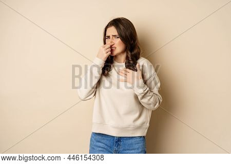 Woman Expressing Disgust Of Bad Disgusting Smell, Close Nose And Grimaing From Dislike, Standing Ove