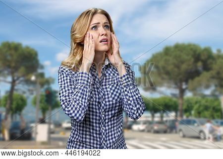 Stressed Young Woman Touching Her Face While Standing Outdoors.