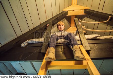 A Boy Sits On A Bed On The 2nd Floor In A Glamping. Rest In The Mountains In Glamping. Cozy House In