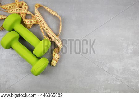 Dumbbells, Measuring Tape On A Gray Textured Background. Fitness, Sports Nutrition