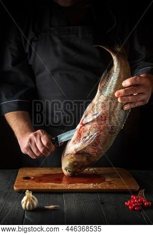 The Chef Prepares Silver Carp In The Restaurant Kitchen. Preparation For Cutting Fish With A Knife. 