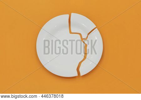 Top View On Broken Circle White Plate On Yellow Background. The Plate Broke Into Three Pieces.