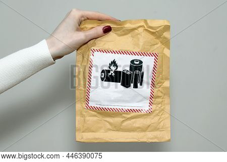 Female Hand Holding Envelope With Battery Warning Label On Secure Package For Transporting Flammable