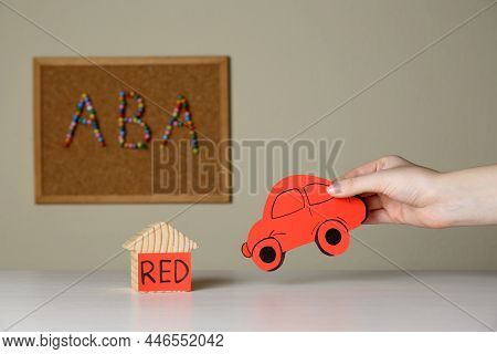 Woman Holding Red Car Near Wooden House And Cork Board With Abbreviation Aba (applied Behavior Analy