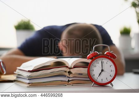 Close-up Of Tired Student Take Nap Behind Pile Of Textbooks On Table. Sleepy Man Resting During Educ