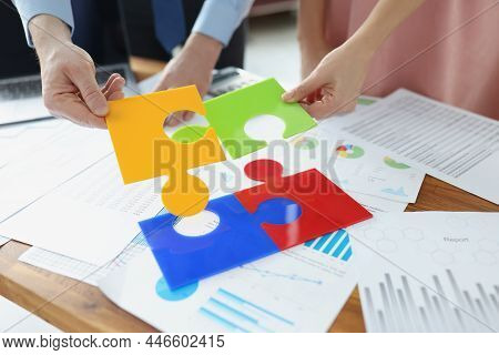 Close-up Of Coworkers Solving Jigsaw Puzzle On Workplace, Colourful Parts. Put Puzzles Into One, Who
