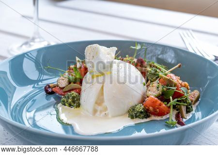 Salad With Buratta Cheese On Blue Plate On Wooden Table
