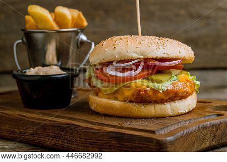 Burger With Fish Cutler And French Fries And Sause On Wooden Table