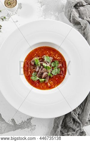Authentic georgian beef soup Kharcho. Georgian lamb and rice soup. Caucasian dish - kharcho soup with rice, beef and coriander leaves. Kharcho in white plate on stone table