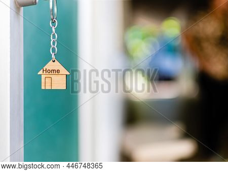 House Key With House Keyring In The Keyhole On The Glass Door. The Concept For Purchasing Real Estat