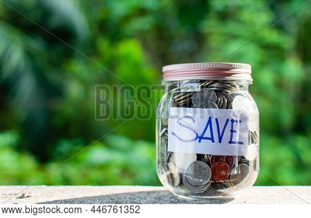 Blurred Background, Coins And Text Save In A Glass Jar Placed On A Wooden Table. Concept Of Saving M