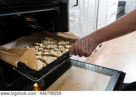 Close Up View Of The Male Person In Apron Standing In Front Of The Open Oven And Putting Pastry On T