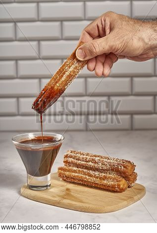 Dipping Churro In Chocolate Sauce. Wooden Board With Churros