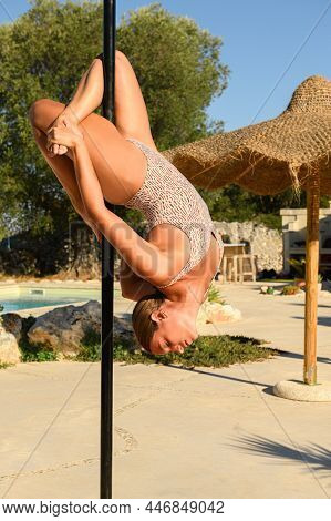Young Beautiful Pole Dancer Making A Pose On A Pole. Summer Outdoors Technique Training In Sunset Li