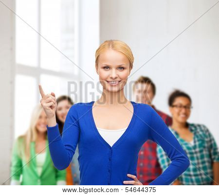 advertisement concept - attractive young woman in casual clothes pointing her finger up