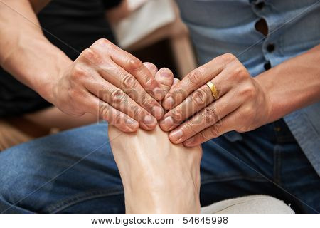 Masseur making a traditional chinese foot massage to adult leg and foot