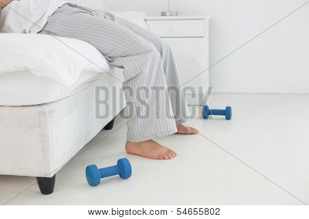 Side view low section of a young man in pajama lying in bed at a bright home