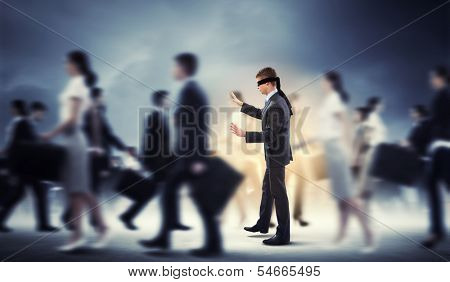 Image of businessman in blindfold walking among group of people