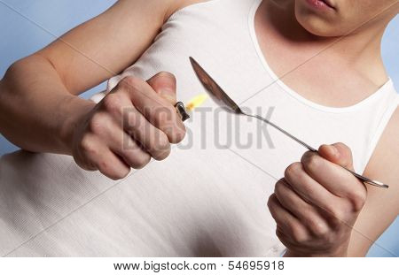 Man with a hardline drug addiction heating drugs in a spoon over a flame 