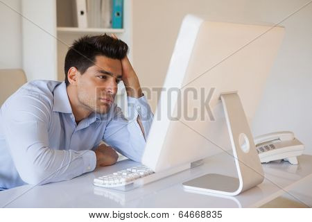 Casual businessman slumped at his desk in his office