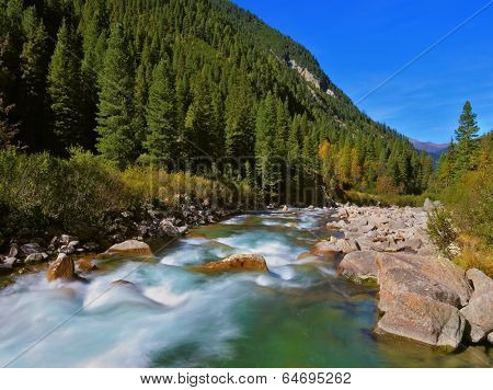 Stormy and frothy mountain stream. Cascades of cold water at the source of the famous Krimml waterfalls. Pastoral in the Alpine mountain valley in Austria