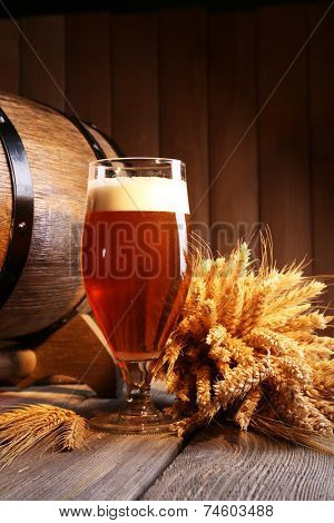 Beer barrel with beer glass on table on wooden background
