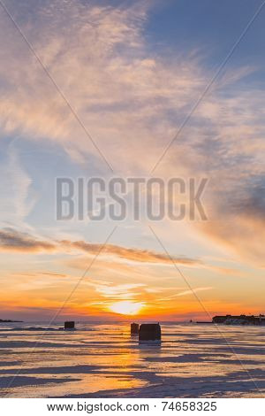 Ice fishing at sunset along the shores of rural Prince Edward Island.