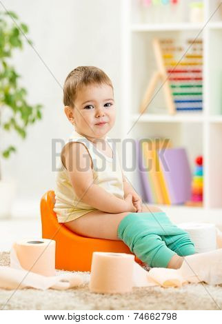 smiling child sitting on chamber pot with toilet paper