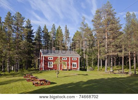 A red building, lawn this side the forest.
