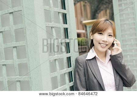 Asian business woman use cellphone in modern city, closeup portrait shot at Xinyi business district, Taipei, Taiwan.