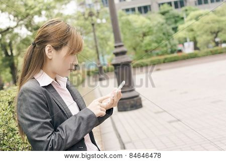 Asian business woman use cellphone in modern city, closeup portrait shot at Xinyi business district, Taipei, Taiwan.