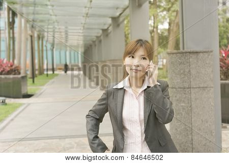 Asian young business woman use cellphone at the street, shot at Xinyi business district, Taipei, Taiwan.