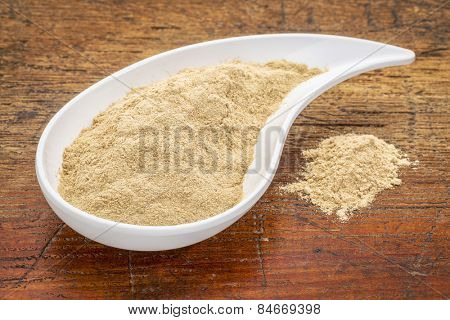 maca root powder in a teardrop shaped bowl against grunge wood