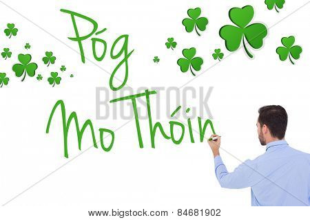 Rear view of a businessman writing with marker against shamrocks