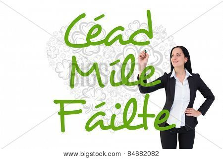 Pretty businesswoman writing with marker against shamrock heart