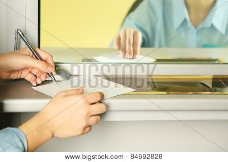 Teller window with working cashier and female hands with claim check. Concept of payment of utilities