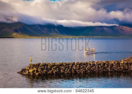 White fishing boat in the harbor pier fishing village Arnastapi. Sunset on the sea fjord in Iceland