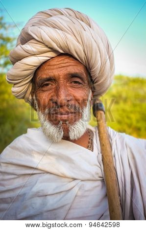 GODWAR REGION, INDIA - 14 FEBRUARY 2015: Elderly Rabari tribesman with white turban and blanket around the shoulders and axe. Rabari or Rewari are an Indian community in the state of Gujarat.