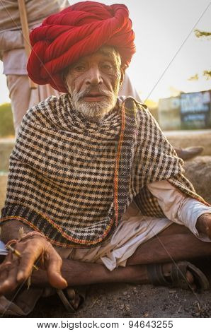 GODWAR REGION, INDIA - 14 FEBRUARY 2015: Elderly Rabari tribesman with red turban and blanket around the shoulders smokes beedi. Rabari or Rewari are an Indian community in the state of Gujarat.