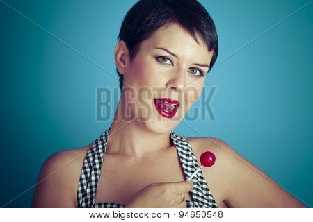 Sugarplum, happy young woman with lollypop  in her mouth on blue background