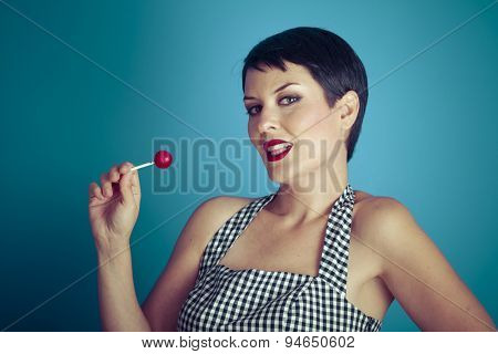 Sugarplum, happy young woman with lollypop  in her mouth on blue background